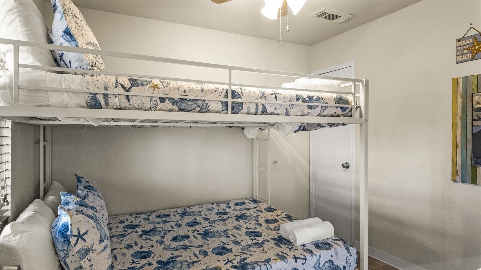 A bunk bed room with a nautical theme, including a bed with a blue and white pattern and starfish pillows.