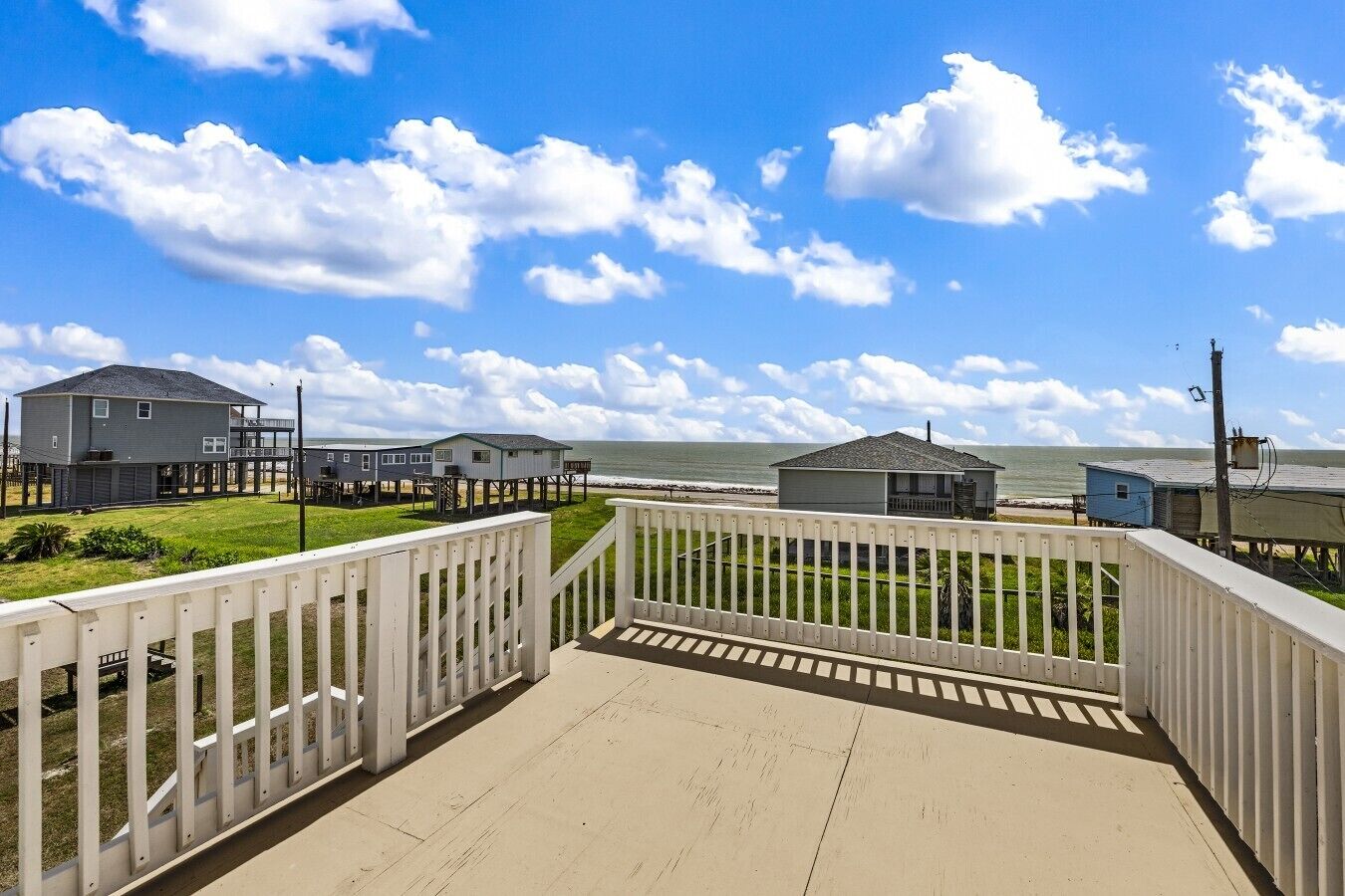 A beachfront property with a deck, a grassy area, and multiple buildings including a house and a small structure.