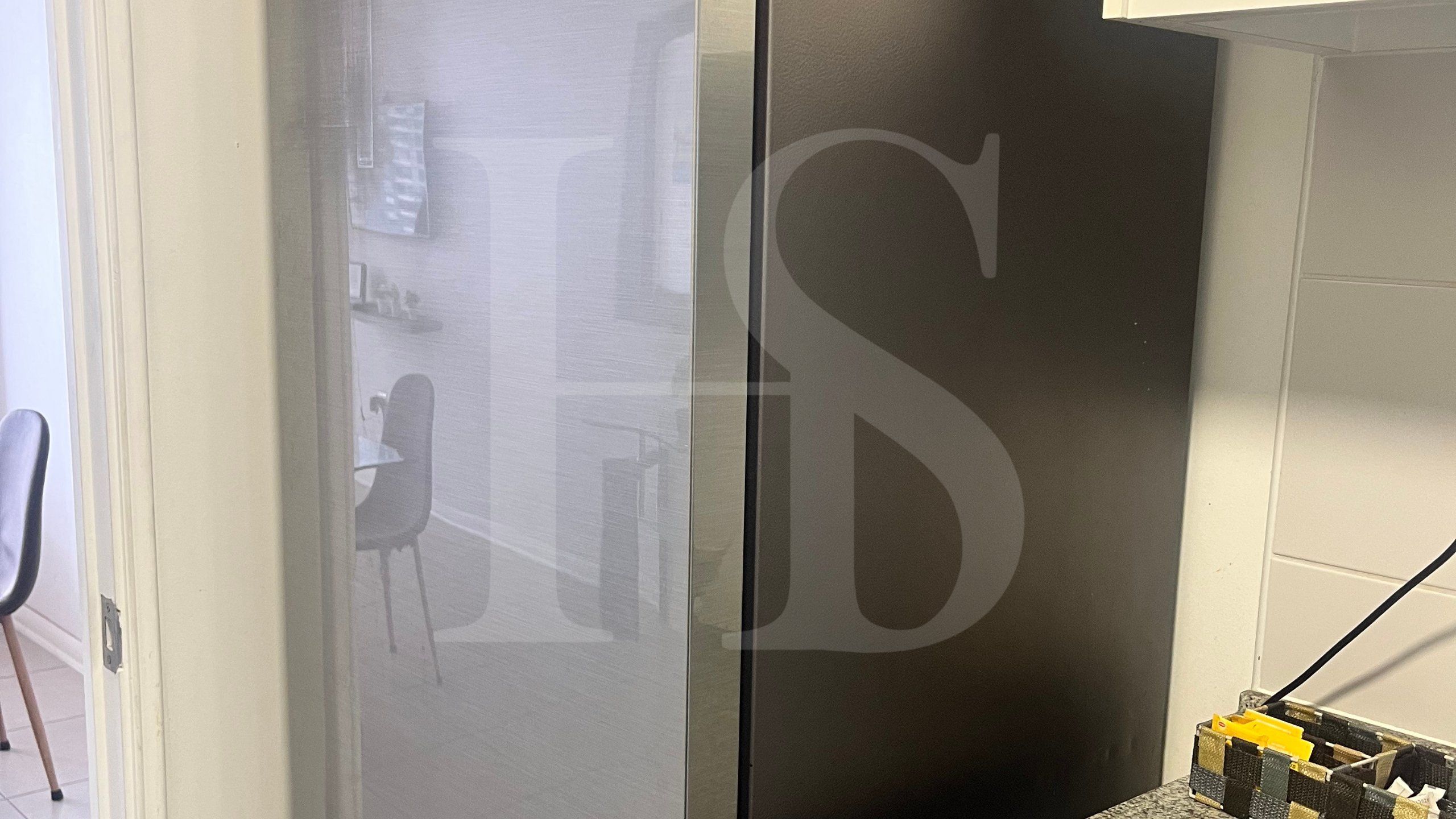 A room with a large mirror, a door, and a partial view of a bed.