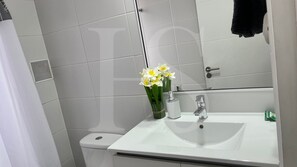 A bathroom with a white sink, a mirror, and a toilet. There is a bouquet of flowers on the sink.
