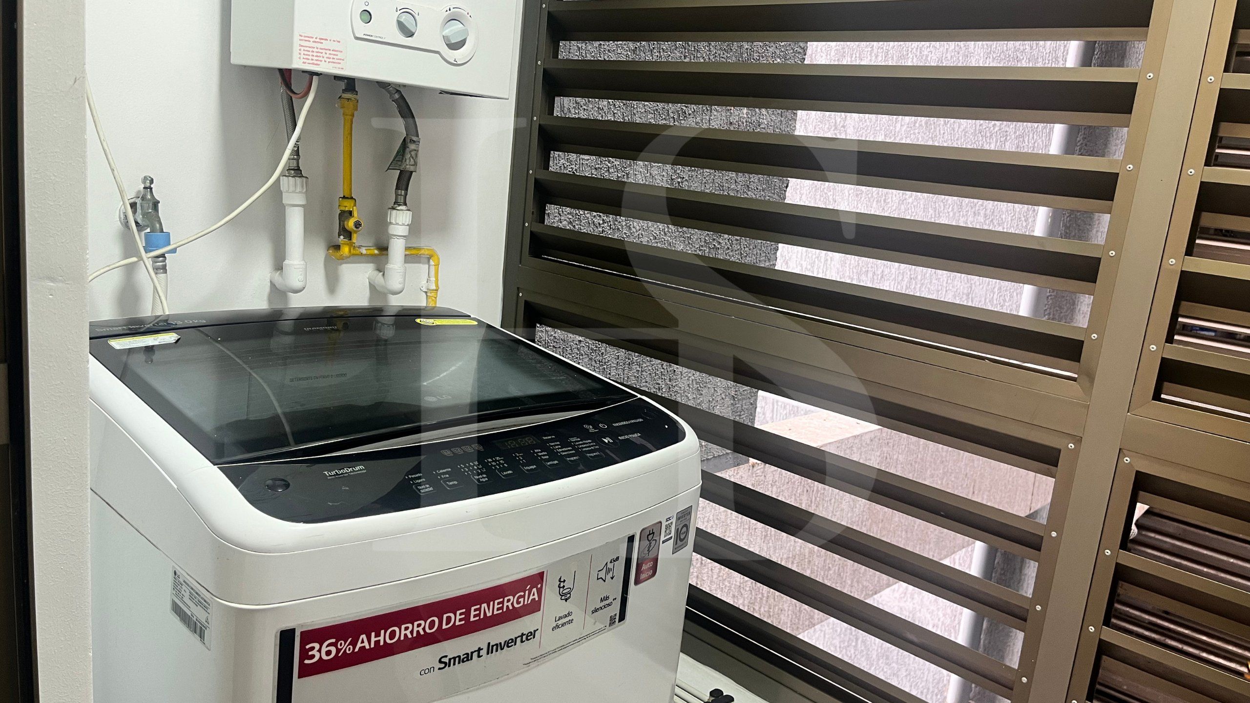 Un inversor inteligente blanco con pantalla digital y panel de control, conectado a un calentador de agua con tuberías.