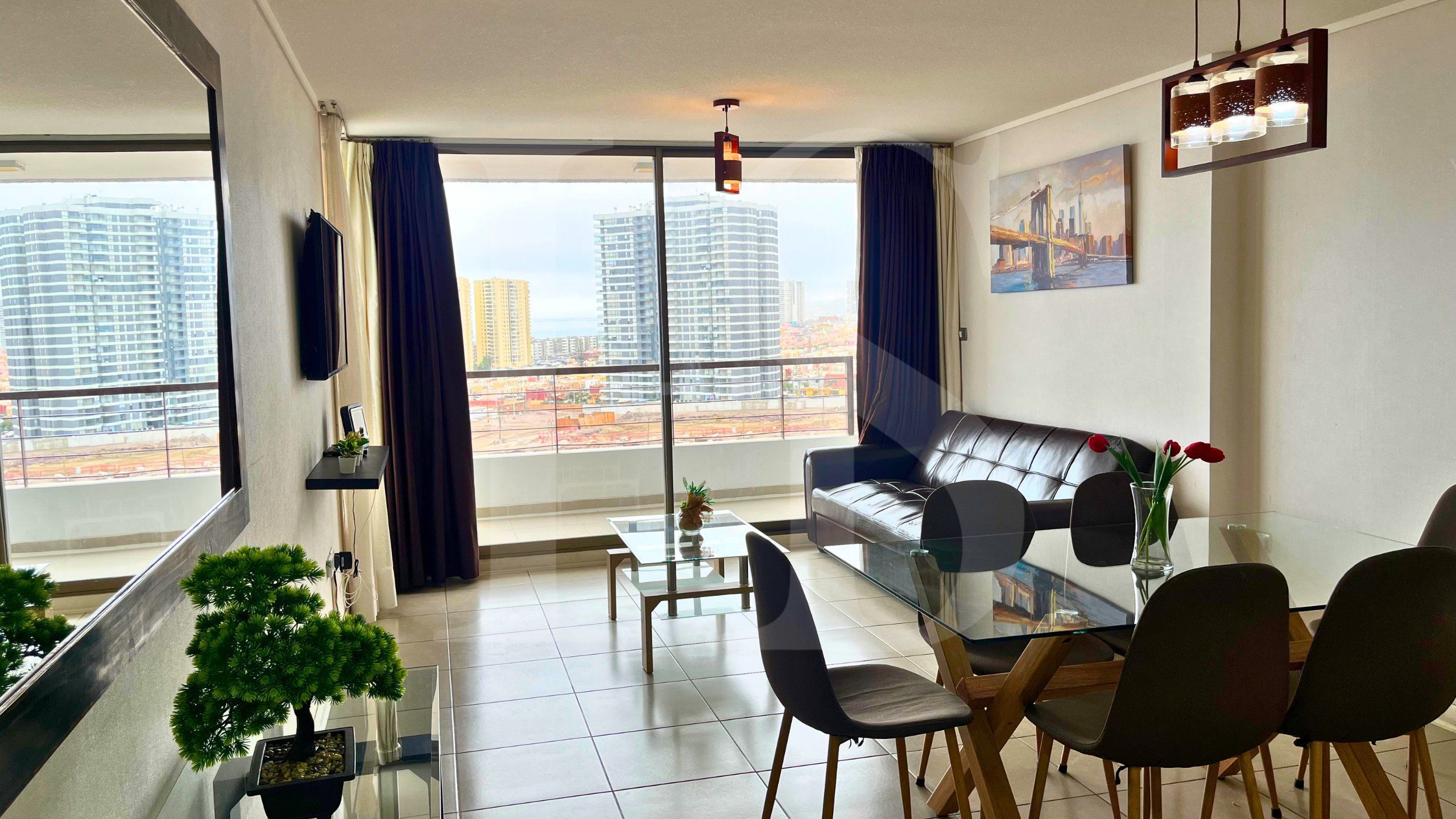 Una sala moderna con una mesa de comedor de vidrio, un sofá y vistas a rascacielos.