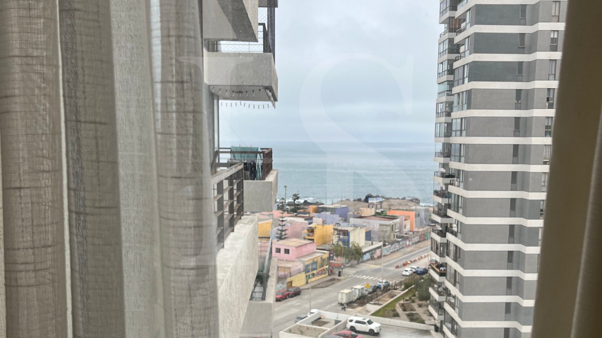 Um edifício alto com várias varandas com vista para a paisagem urbana e um corpo de água.