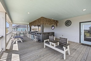 Un espace extérieur abrité, doté d’un bar, de sièges et d’un toit de chaume.