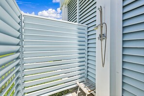 A balcony with a metal railing, a hose, and a wooden bench. - Regal Gal | Bird Watcher`s Coastal Escape (Galveston)