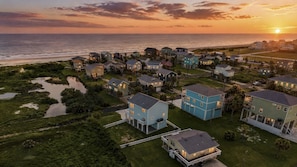 A coastal residential area with houses, a beach, and a sunset. - Regal Gal | Bird Watcher`s Coastal Escape (Galveston)
