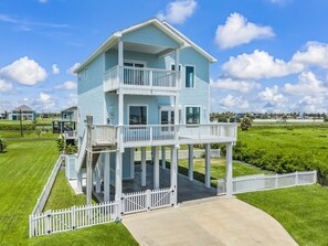 A two-story house with a balcony, a fenced yard, and a clear sky. - Regal Gal | Bird Watcher`s Coastal Escape (Galveston)