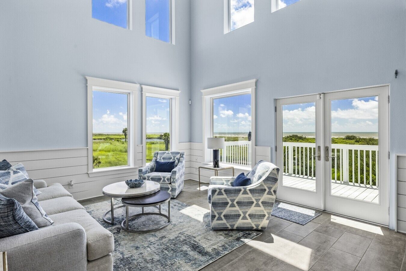 A spacious room with a large window, a sofa, a chair, and a small table.