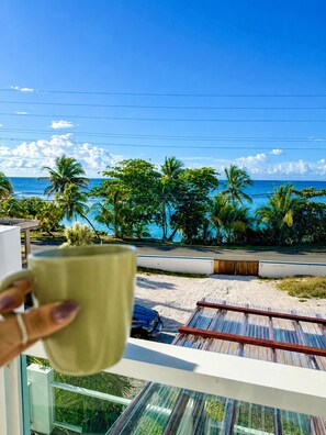 Ein Balkon mit Blick auf einen Strand, Palmen und das Meer.
