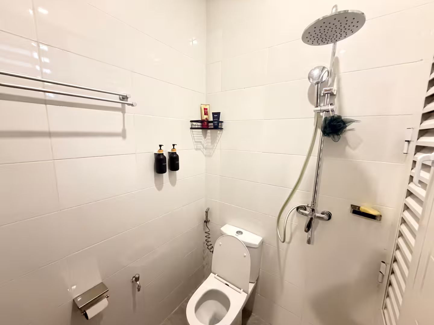 Ein kleines, modernes Badezimmer mit Toilette, Dusche und Handtuchhalter.