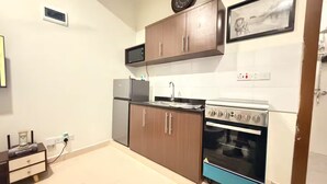 Una cocina compacta con horno empotrado, microondas y refrigerador.