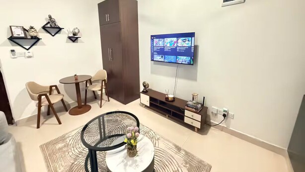 Una sala de estar moderna con televisor, asientos y un mueble de almacenamiento.