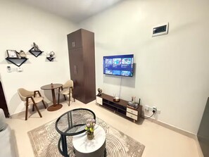 A modern living room with a TV, seating, and a cabinet.