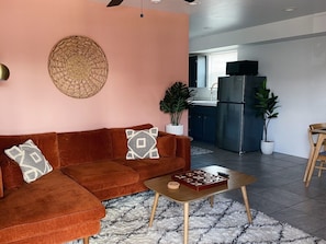 Ein Wohnzimmer mit einem braunen Sofa, einem Couchtisch und einer Küche im Hintergrund.