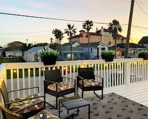 Eine Terrasse mit Gartenmöbeln, ein weißer Zaun und ein Blick auf Gebäude im Hintergrund.