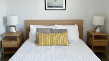 A hotel room with a large bed, two bedside tables, a framed picture on the wall, and a lamp on each table.