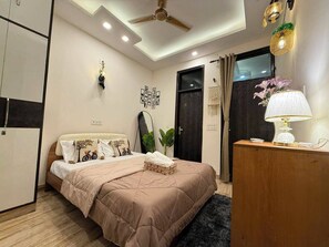 A bedroom with a bed, bedside table, lamp, and a mirror.