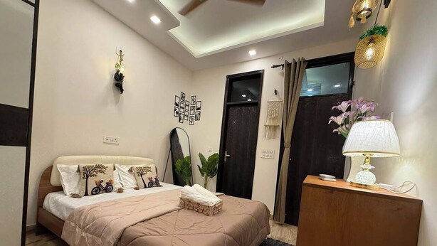 Quarto com cama, mesa de cabeceira, luminária e detalhes decorativos nas paredes.