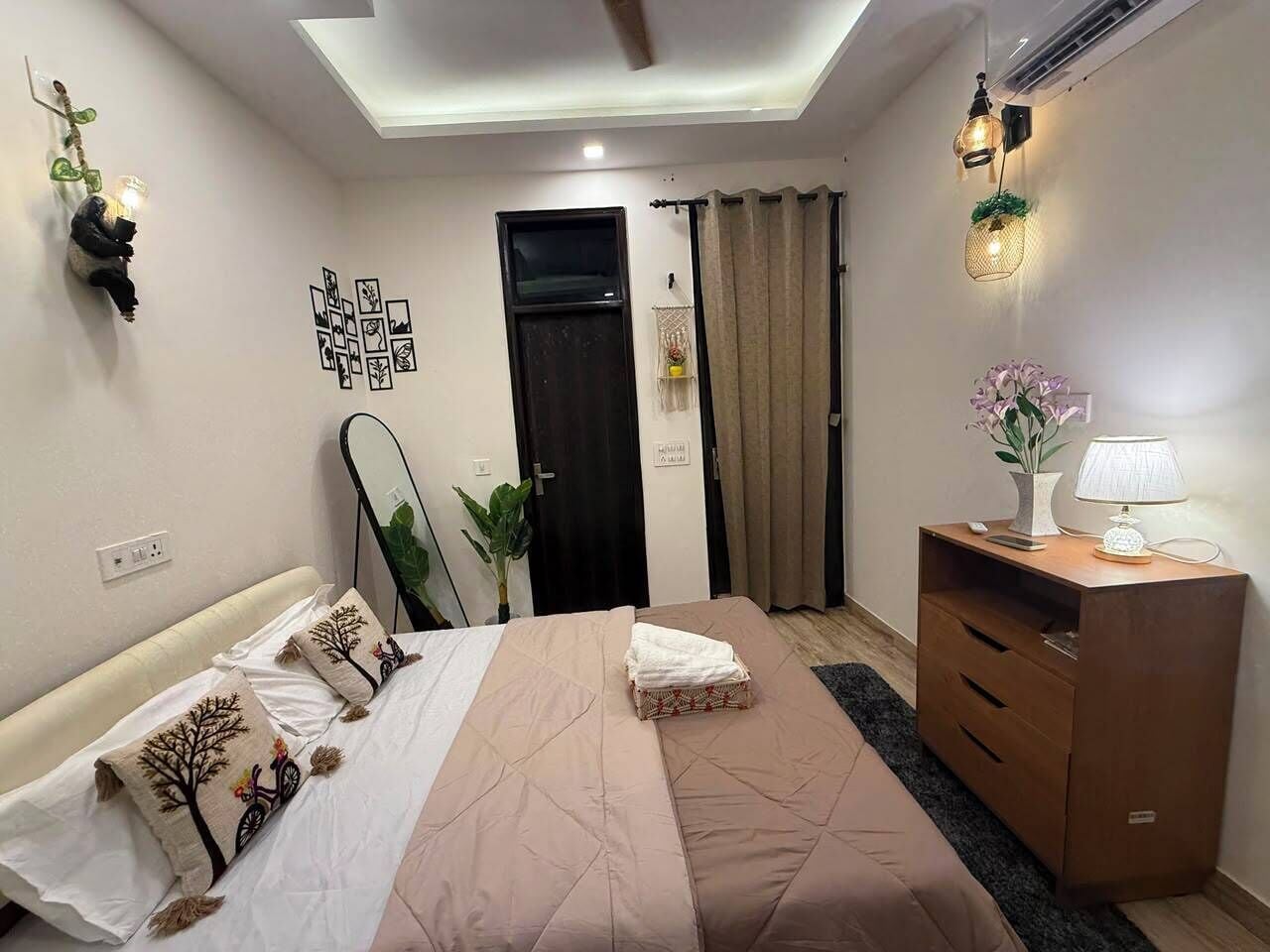 A bedroom with a bed, bedside table, lamp, and a mirror.