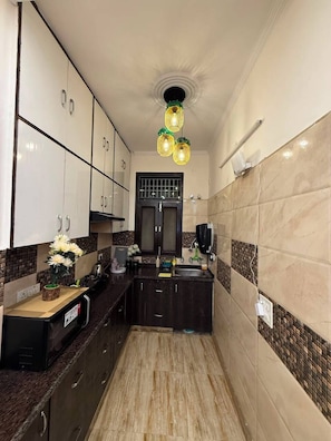 Cocina estrecha con armarios oscuros, encimera negra y salpicadero de azulejos.
