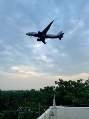 Ein Flugzeug am Himmel mit blauem Himmel und Bäumen im Hintergrund.