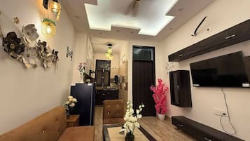 Una sala de estar moderna con un sofá, una mesa de comedor y un televisor de pantalla plana montado en la pared.