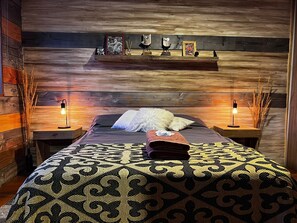 A cozy bedroom with a wooden headboard, a patterned bedspread, and two bedside lamps. - Ideal apartment for a couple with views of the lake and the hills in Villa la Angostura (Villa la Angostura)