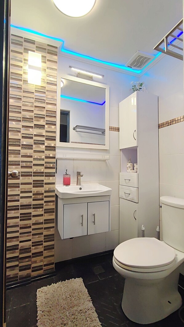 A modern bathroom with a white sink, mirror, and toilet.