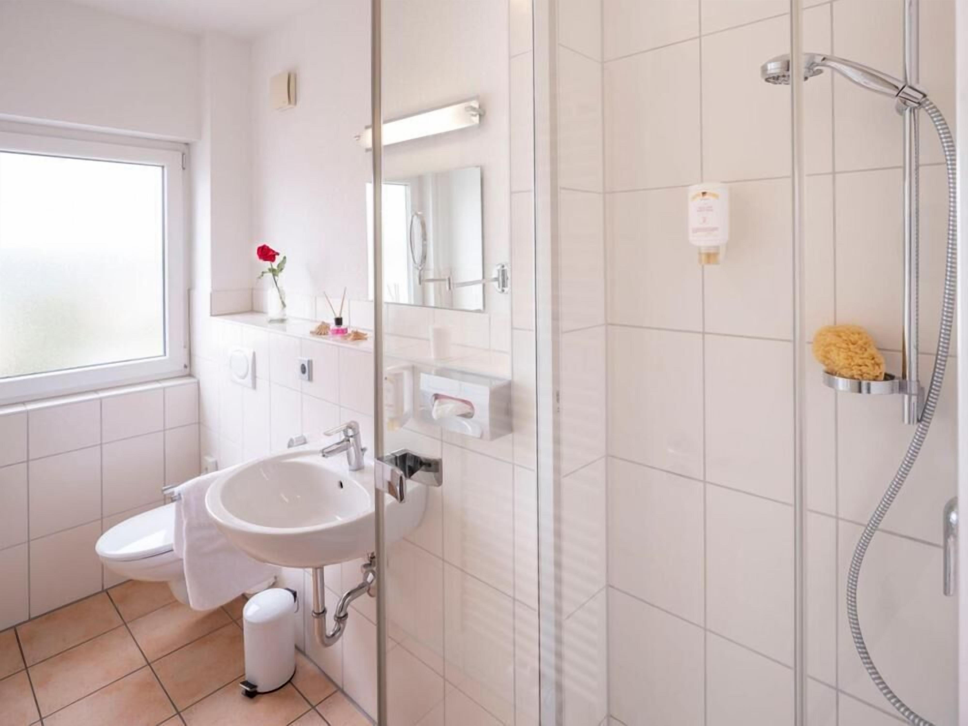 A modern bathroom with a toilet, sink, and shower.