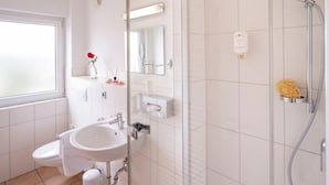 A modern bathroom with a toilet, sink, and shower. - Hotel Berkheimer Hof (Esslingen am Neckar)