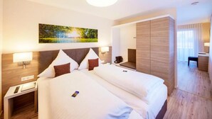 A hotel room with a large bed, bedside tables, a nightstand, a desk, and a mirror. - Hotel Berkheimer Hof (Esslingen am Neckar)