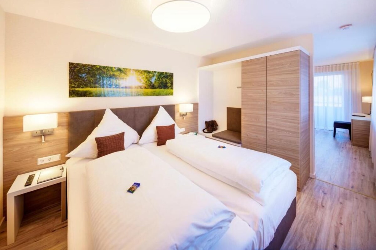 Una habitación de hotel con una cama grande, mesitas de noche, un escritorio y un espejo.