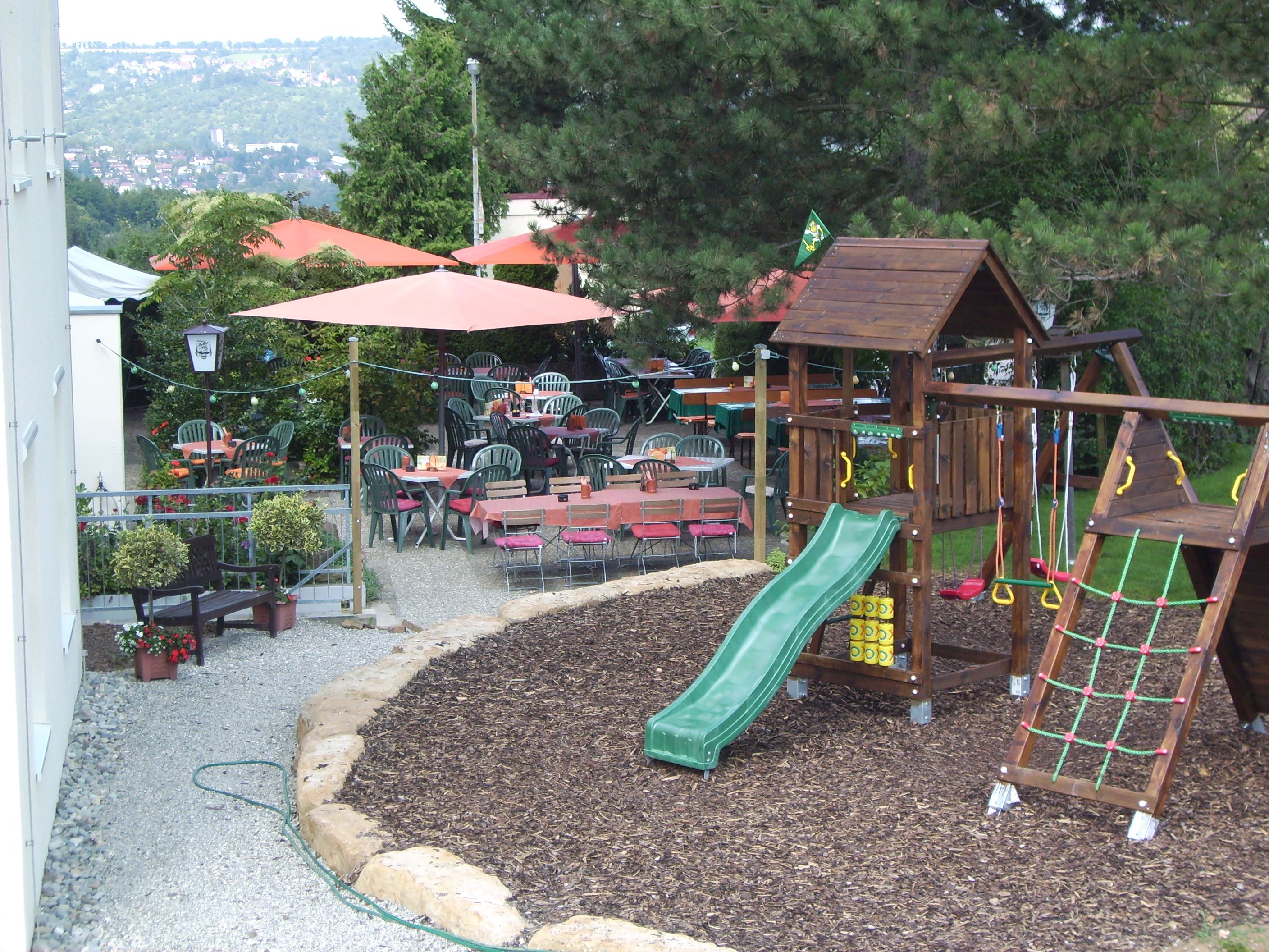 Un espace de jeux pour enfants avec un toboggan, entouré de sièges et de tables en plein air.