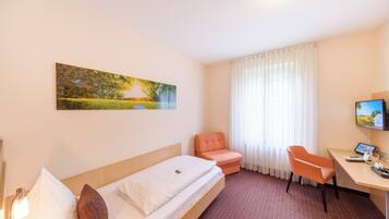 Une chambre d’hôtel avec un lit, un bureau, une chaise, une télévision et un tableau au mur.