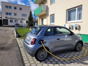 A silver car parked in a driveway with a charging station.