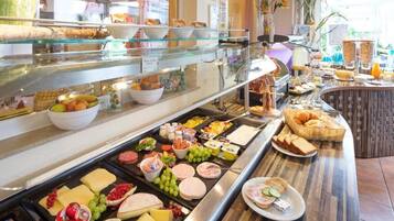Un buffet proposant une variété de plats, notamment des fruits, des fromages et des viandes.
