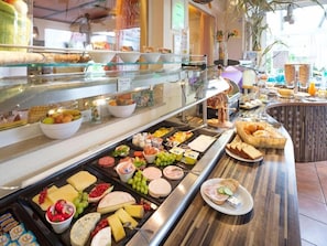 Un bufé con diferentes opciones de comida, incluyendo queso, carnes, frutas y pan.