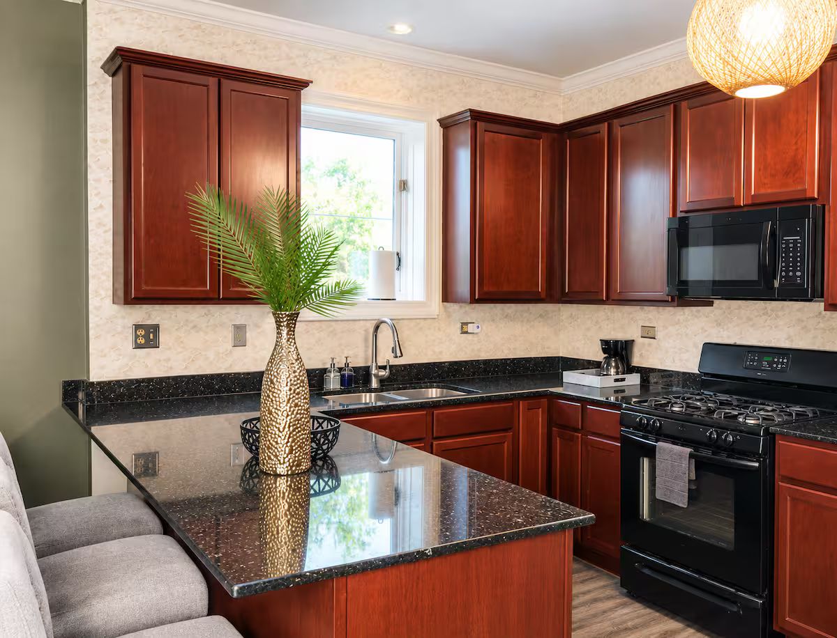 A modern kitchen with dark wood cabinets, a black stove, and a granite countertop.