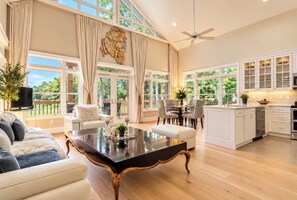 A spacious living area with a large black coffee table, white sofas, and a dining area with patterned chairs. - Luxury Fairway Escape-Golf and Water Views (Chapel Hill)