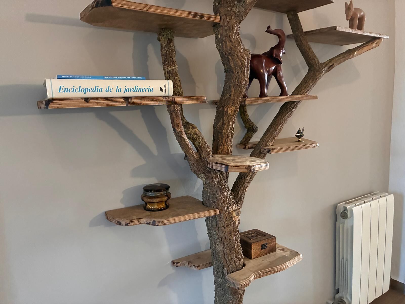 Een houten rek in de vorm van een boom met verschillende spullen op de takken.