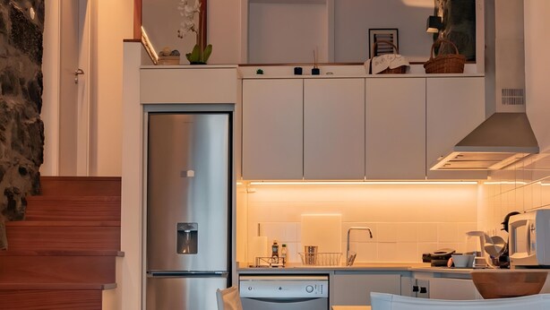 Eine moderne Küche mit eingebautem Geschirrspüler, einem Edelstahlkühlschrank und einem Essbereich mit Holztisch und -stühlen.