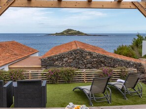 Eine Terrasse mit Steinmauer, Holzterrasse und Meerblick.