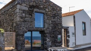 Ein Steinhaus mit Glastür und Blick aufs Meer.