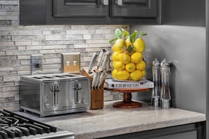 A kitchen counter with a toaster, a knife block, a glass container with lemons, and salt and pepper shakers.