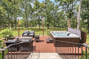 A deck with outdoor furniture, a hot tub, and a wooden deck railing.
