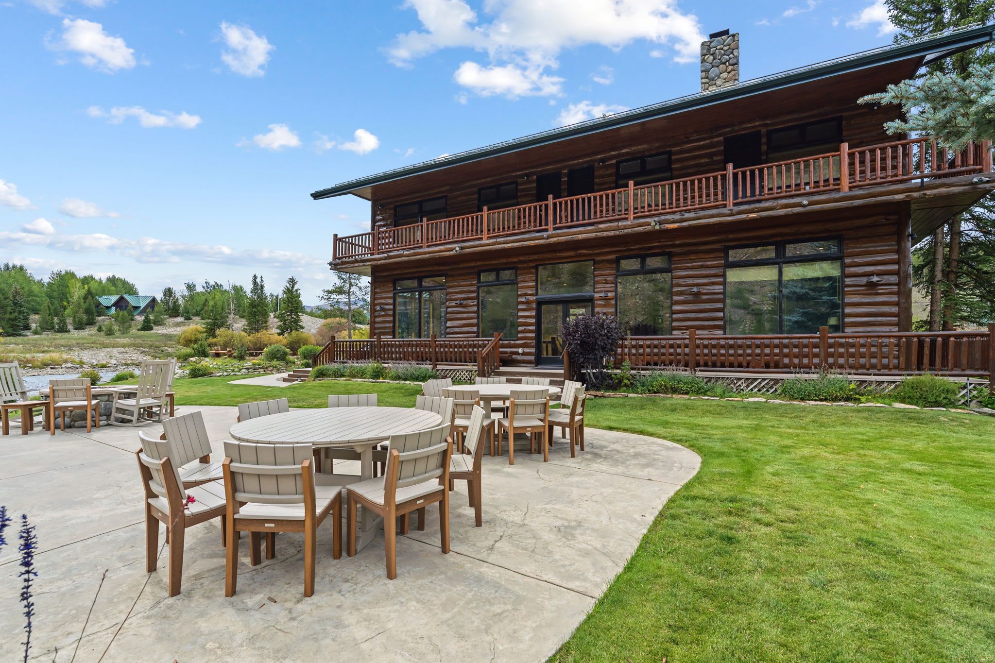 A log cabin with a deck, outdoor seating, and a view of the surrounding landscape.