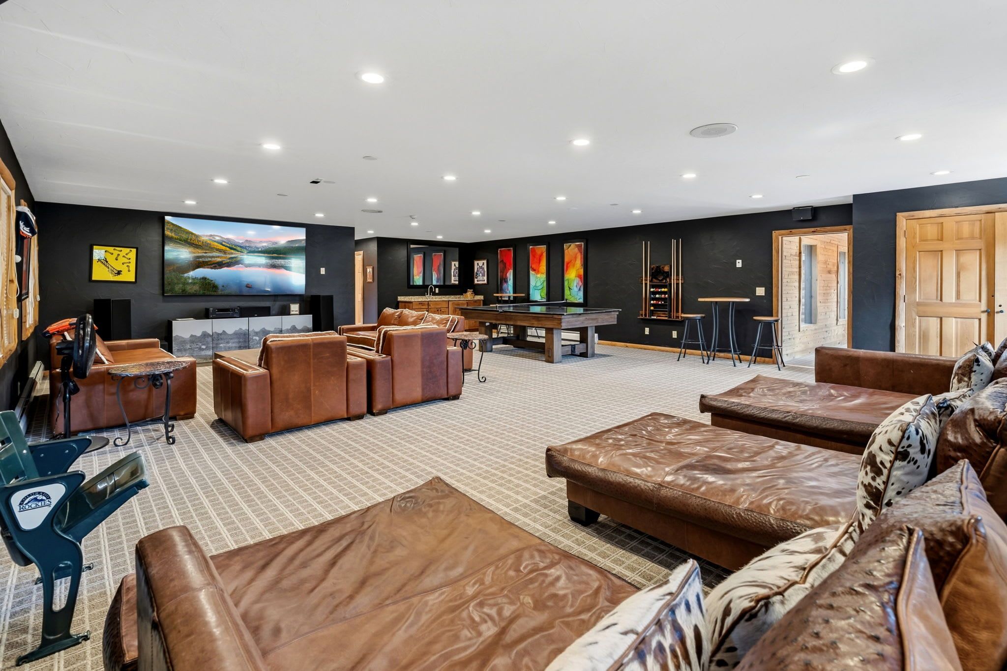 A spacious living area with leather sofas, a pool table, and a flat-screen TV.