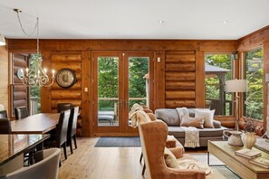 A log cabin interior with a dining area, a sofa, and a coffee table. - Rustic Retreat | 3BR Chalet | Fireplace | 8 guest (Lac-Supérieur)