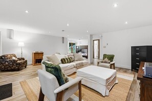 Un salon moderne comprenant un canapé, un fauteuil, une petite table et un téléviseur.
