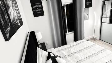 Ein modernes Schlafzimmer mit einem Bett, Vorhängen, einer Wandleuchte und einem Poster.